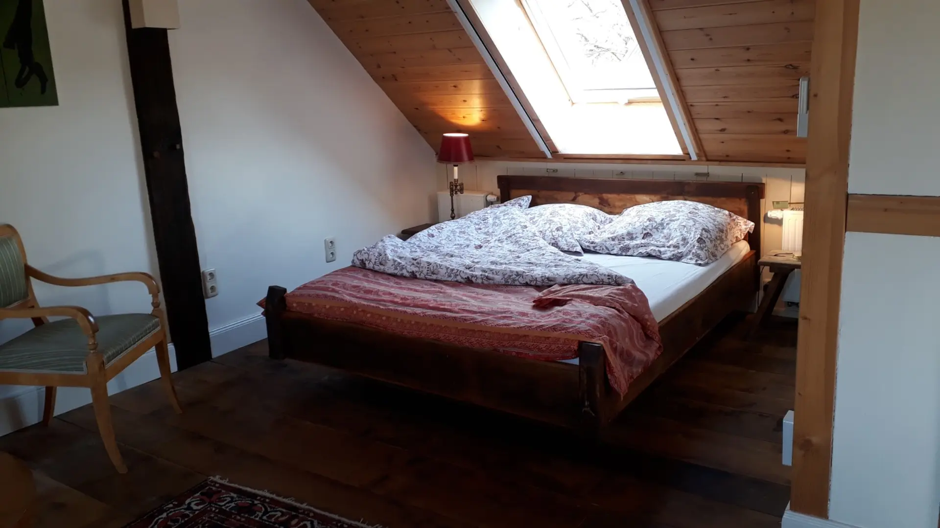 Großes Doppelbett mit Sicht aus dem Dachfenster darüber